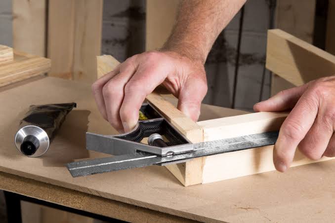 Carpenter measuring and cutting wood in workshop